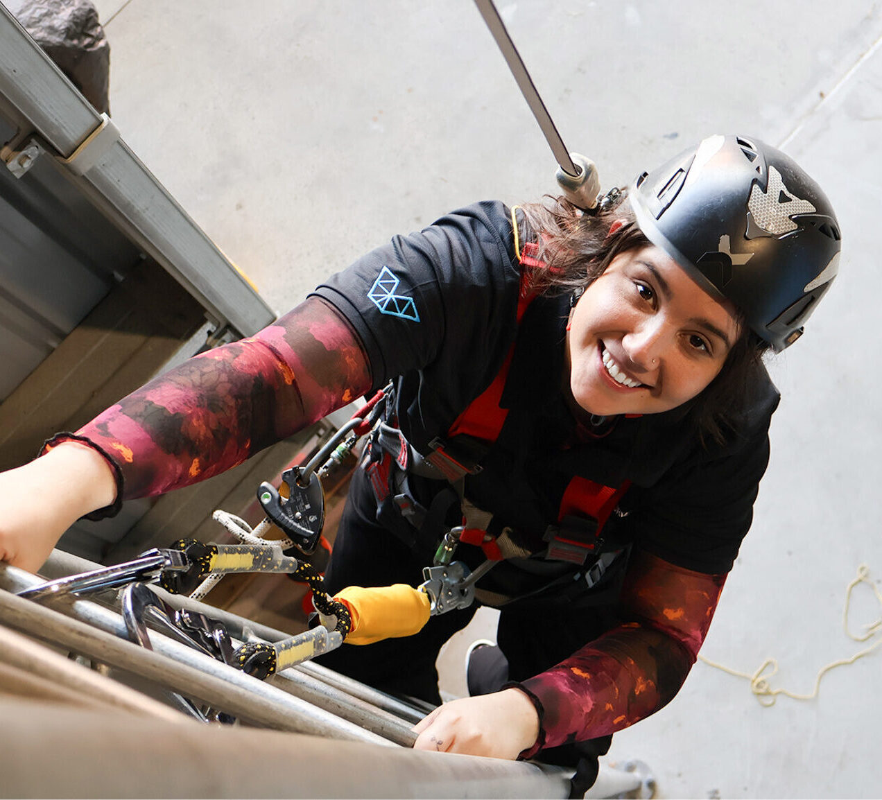 A learner in safety gear and harness climbing a struture