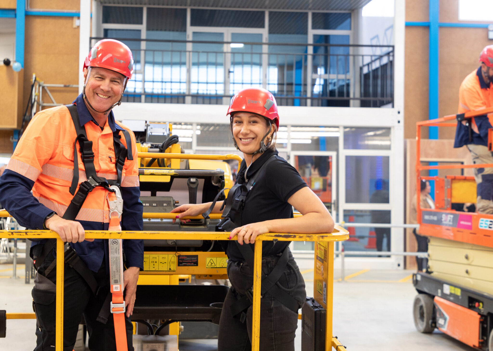Two people smiling, wearing PPE while learning machinery