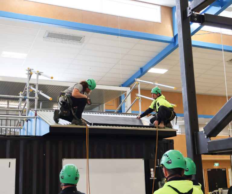 Two learners putting solar panels on a training roof