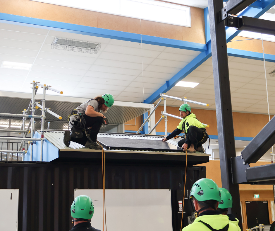 Two learners putting solar panels on a training roof